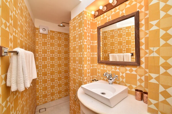 A bathroom with patterned walls, a sink, a mirror, and a towel rack. - Mateus Boutique Hotel (Panaji)