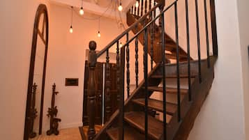 Eine Holztreppe mit schwarzer Geländer und einer Lampe darüber.