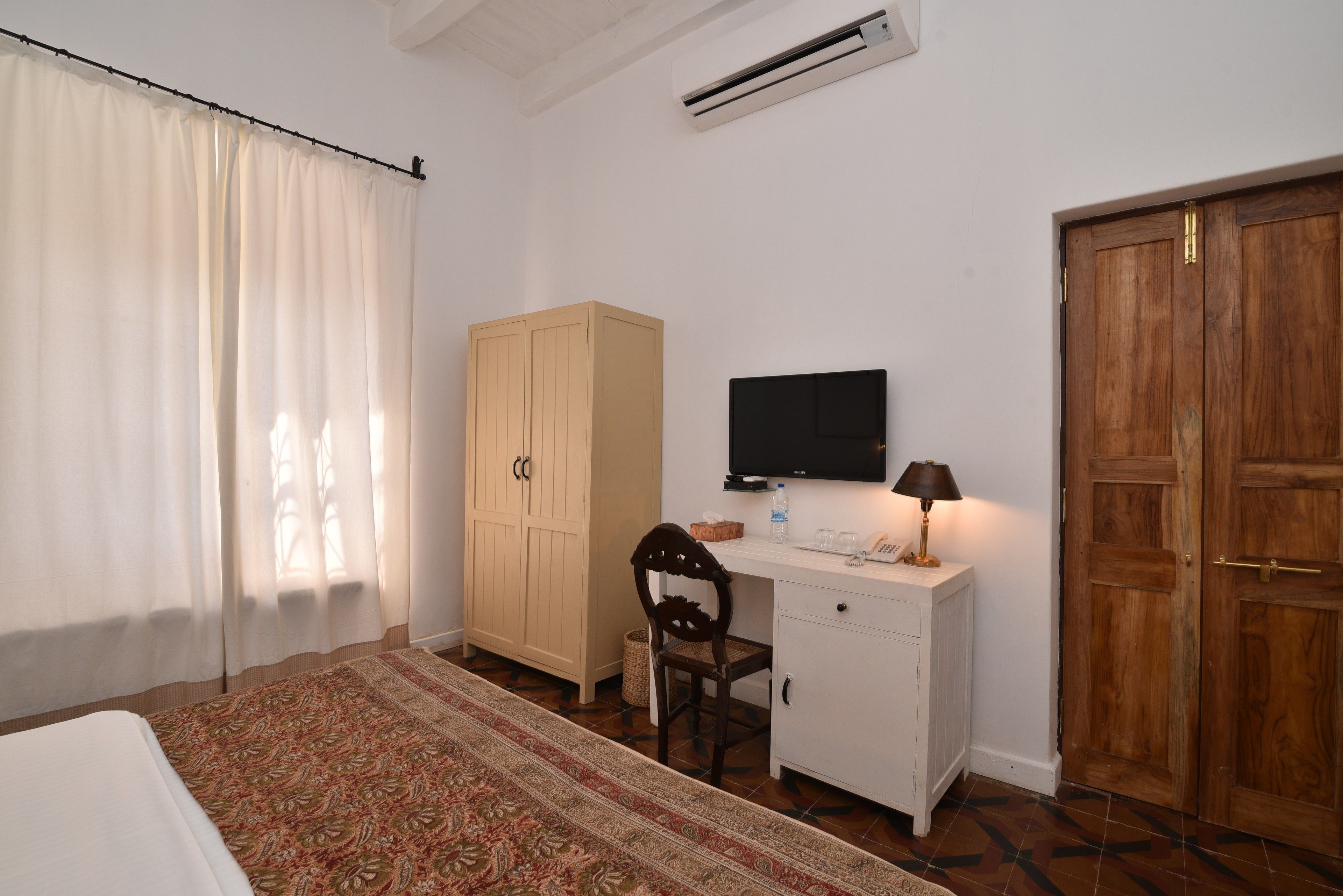 Un dormitorio con cama, escritorio con silla, televisor y armario.