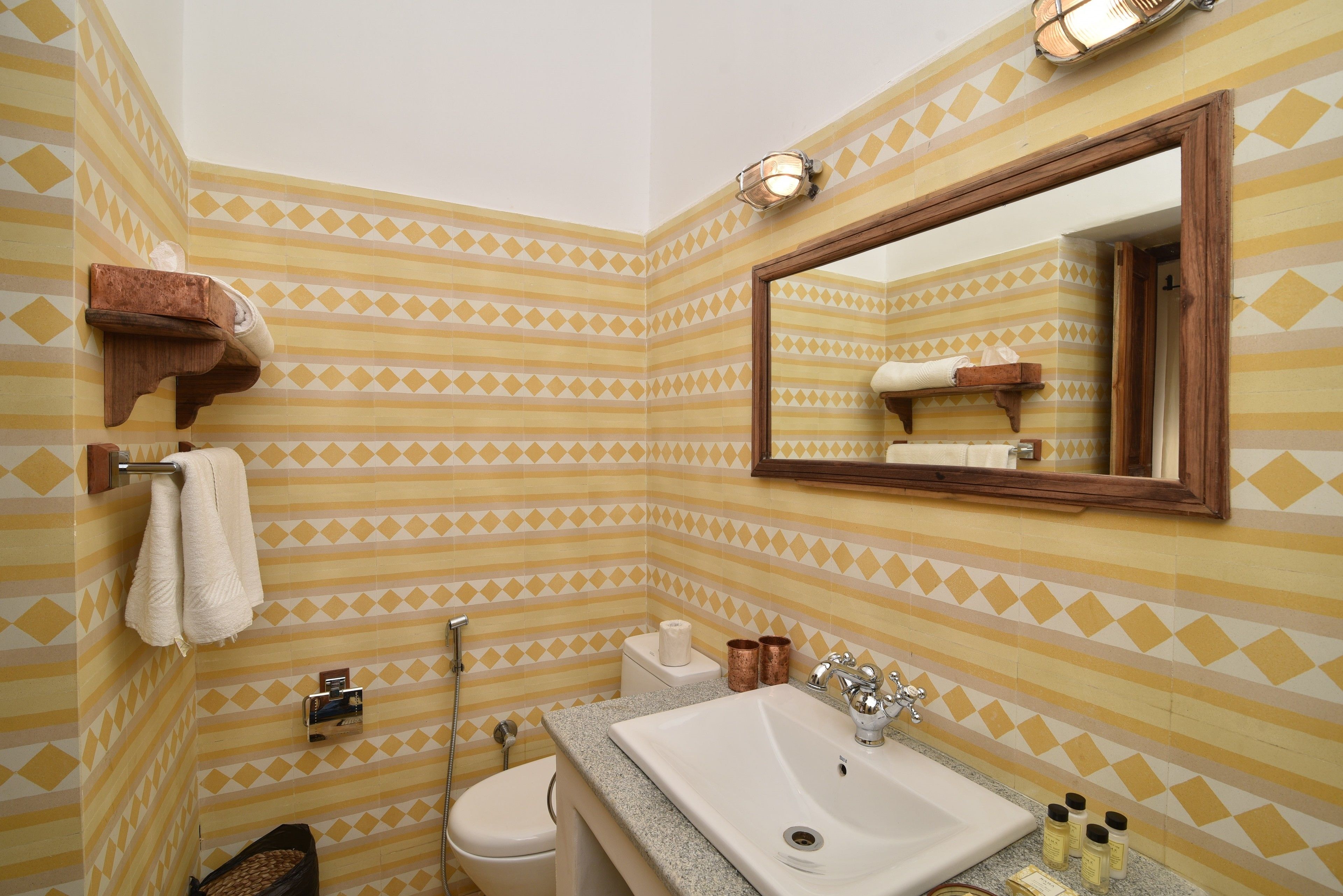 A bathroom with striped tile walls, a sink, a mirror, and a towel rack.