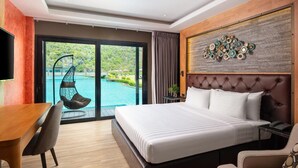 A modern hotel room with a large bed, a dining table, a chair, a hanging chair by the pool, and a view of the pool and greenery outside. - La Isla Pranburi Beach Resort (Sam Roi Yot)