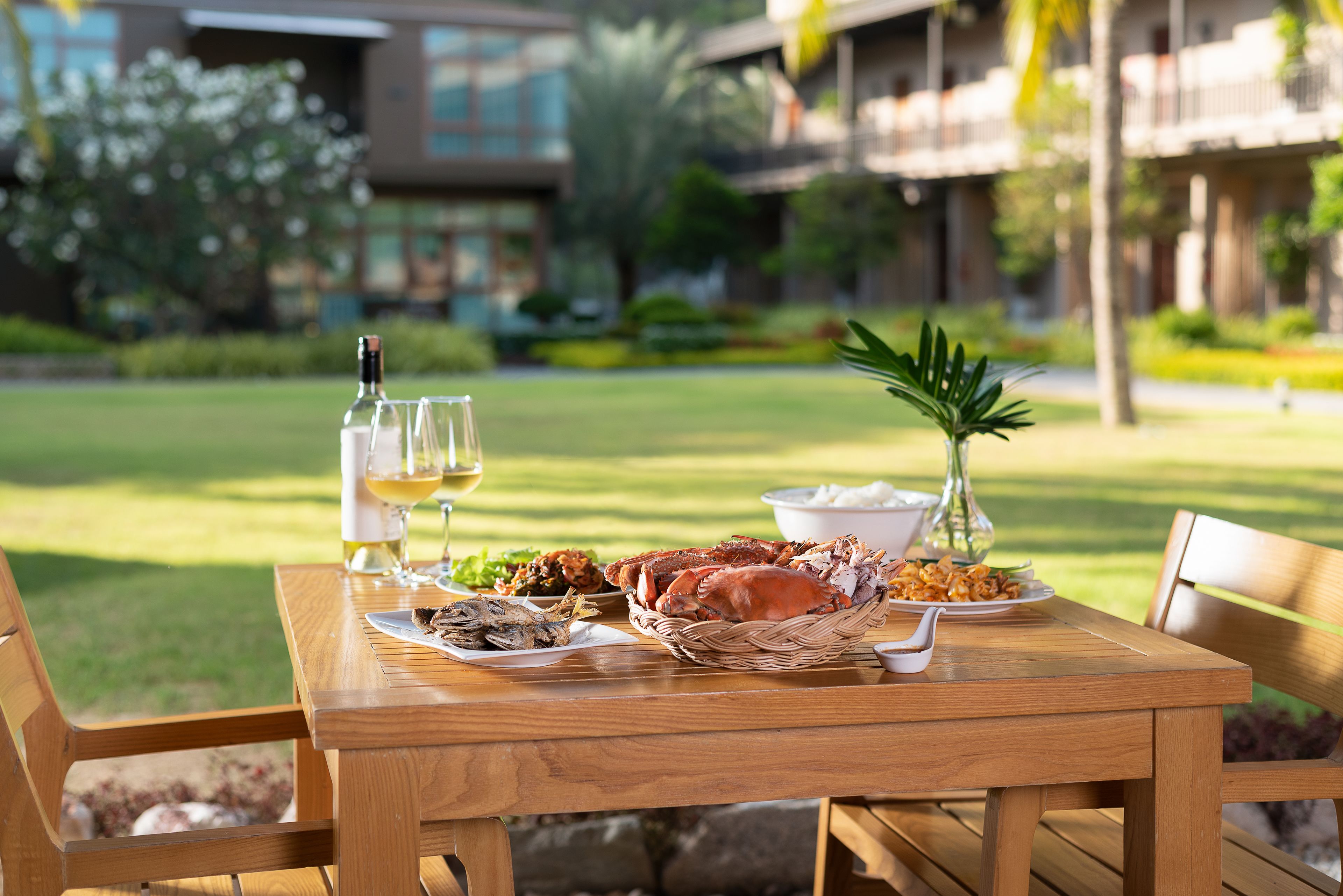 A wooden table set with seafood, a bottle of white wine, and a glass.