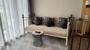 Una habitación con un sofá, una pequeña mesa redonda y un suelo estampado.