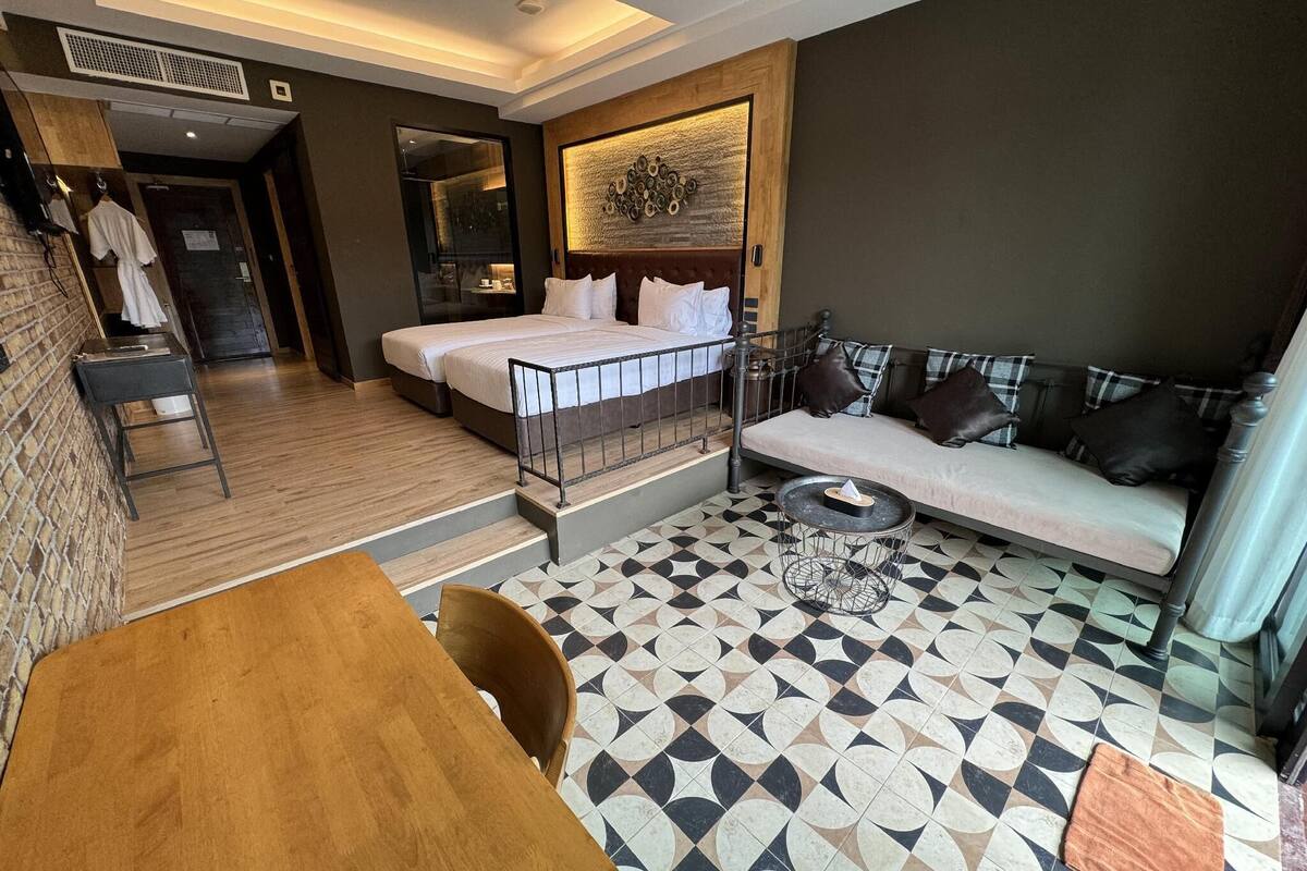 Een moderne hotelkamer met een bed, een sofa, een eettafel en een vloer met een patroon.