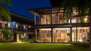 A modern hotel with a spacious outdoor dining area, multiple balconies, and lush greenery. - La Isla Pranburi Beach Resort (Sam Roi Yot)