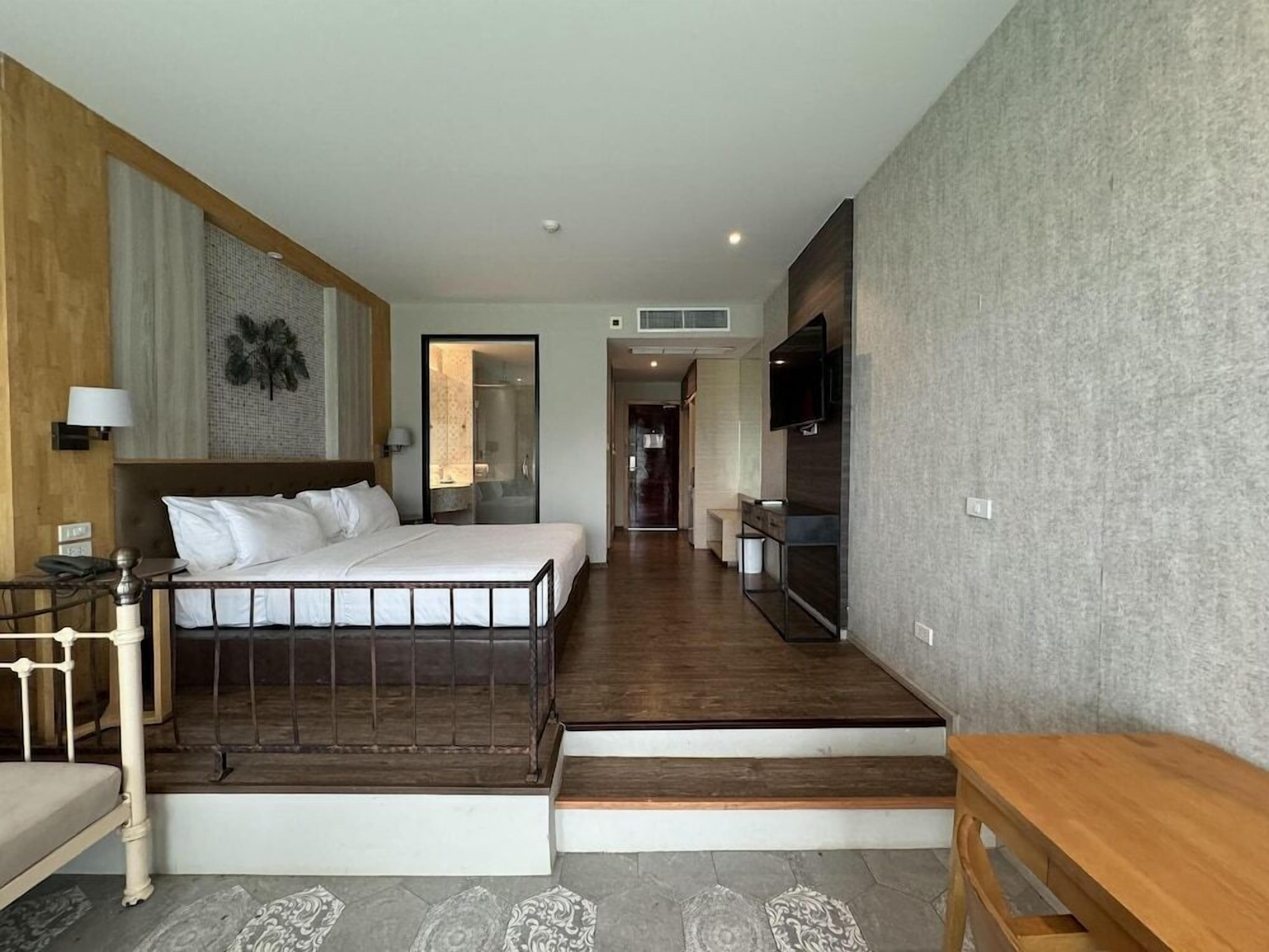 Ein Hotelzimmer mit einem Bett, einem Schreibtisch, einem Sessel, einem Fernseher und einer Treppe, die zu einer weiteren Ebene führt.