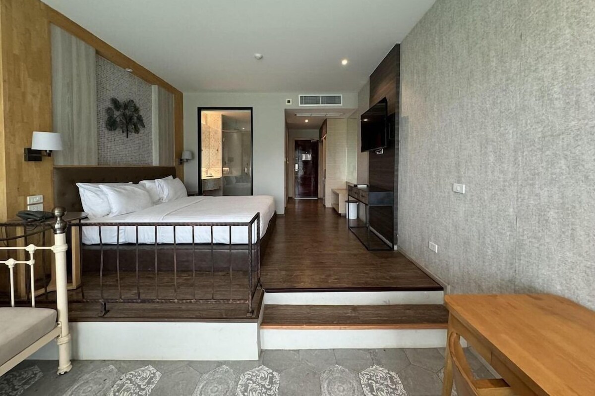 Une chambre d’hôtel équipée d’un lit, d’un bureau, d’une chaise, d’une télévision et d’un escalier menant à un autre étage.