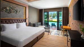 A hotel room with a large bed, a desk, a chair, a TV, and a view of the pool and beach. - La Isla Pranburi Beach Resort (Sam Roi Yot)