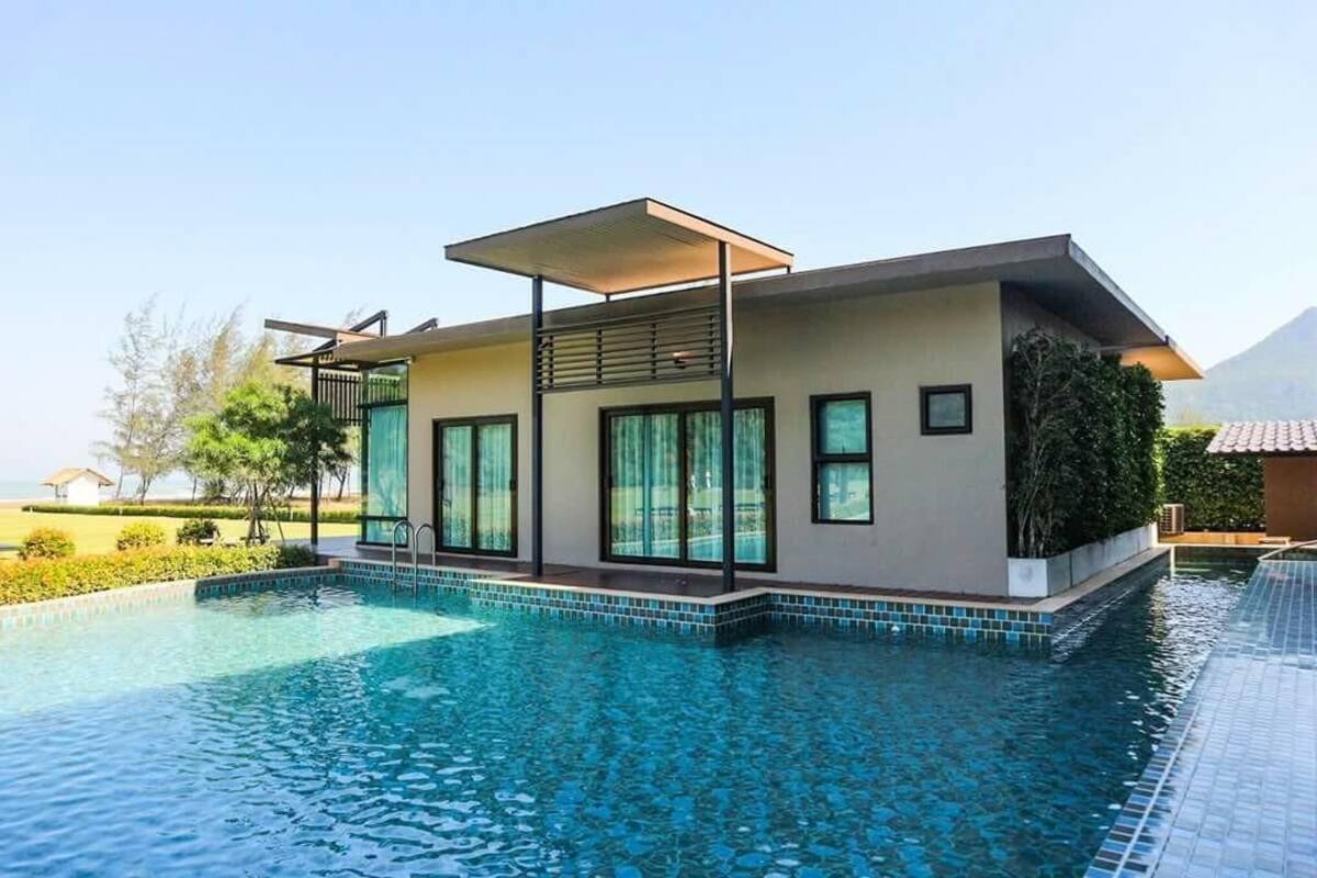 Een modern huis met een zwembad, grote ramen en een overdekt terras.