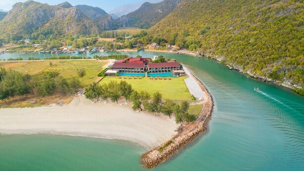 A resort with a swimming pool, a beach, and a mountain backdrop. - La Isla Pranburi Beach Resort (Sam Roi Yot)