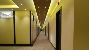 Un pasillo de hotel con piso alfombrado, luces empotradas y puertas a ambos lados.