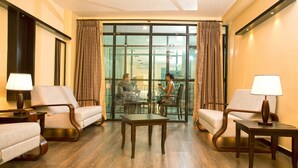Un hall de hotel con zona de estar, una mesa de centro y vistas al comedor a través de amplios ventanales.