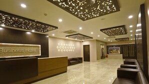 Zona de recepción de un hotel con suelo de mármol, mostrador de recepción y área de estar con sillones de cuero.