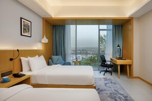 A hotel room with a bed, bedside table, lamp, desk, chair, and a view of the city. - Best Western Siraichuli Hotel (Bharatpur)