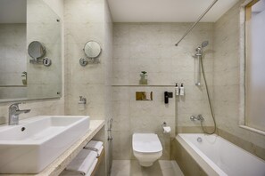 A bathroom with a bathtub, a sink, a toilet, and a shower. - Best Western Siraichuli Hotel (Bharatpur)