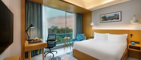 Una habitación de hotel con una cama grande, un escritorio, una silla, un televisor y una ventana con cortinas.