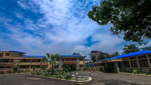 A hotel with a central courtyard, multiple buildings with blue roofs, and a clear sky.