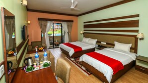 A hotel room with two beds, a desk with a tray of breakfast items, a chair, and a view of the outdoors.