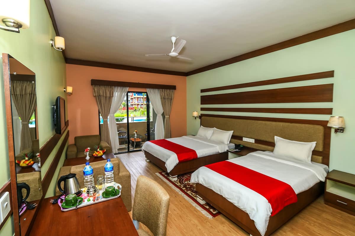 Ein Hotelzimmer mit zwei Betten, einem Schreibtisch mit Frühstücksgebäck und einem Stuhl, mit Blick ins Freie.