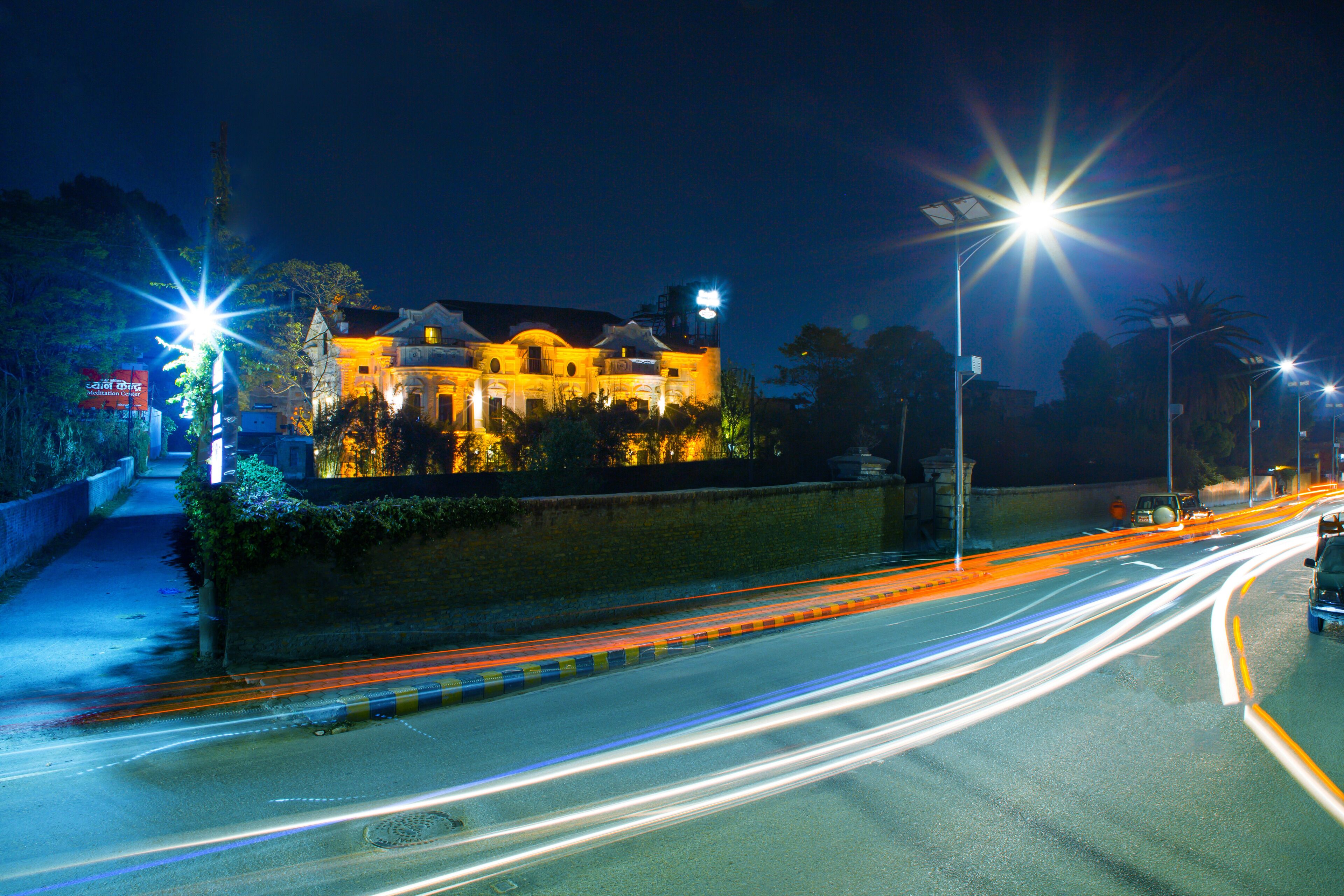 A well-lit building with a prominent entrance and a road with light trails indicating traffic.