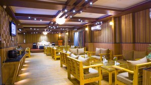 Een restaurant met houten meubels, een televisie en een podium.