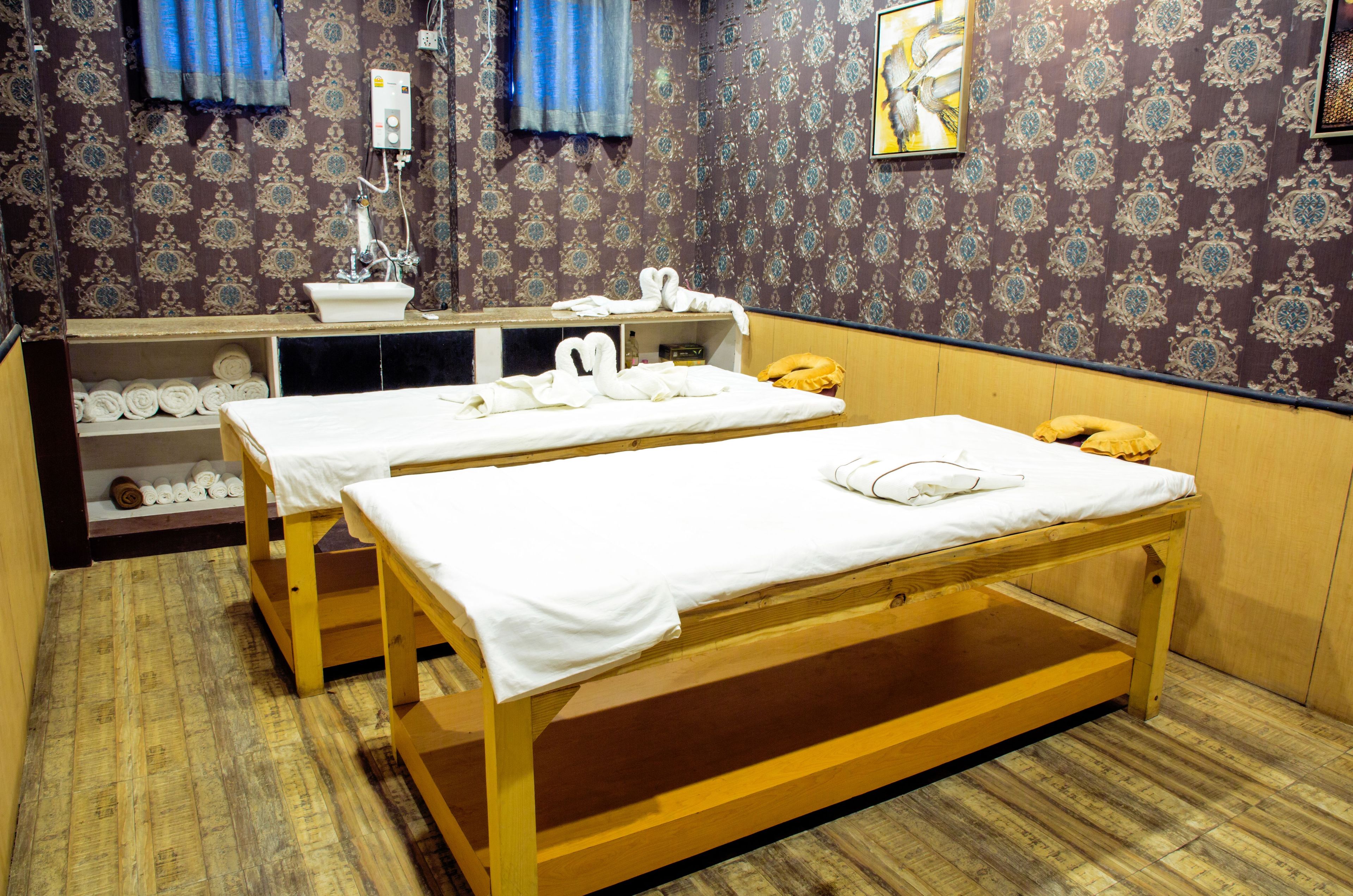 Une chambre avec deux lits en bois, un lavabo et une étagère avec des serviettes.