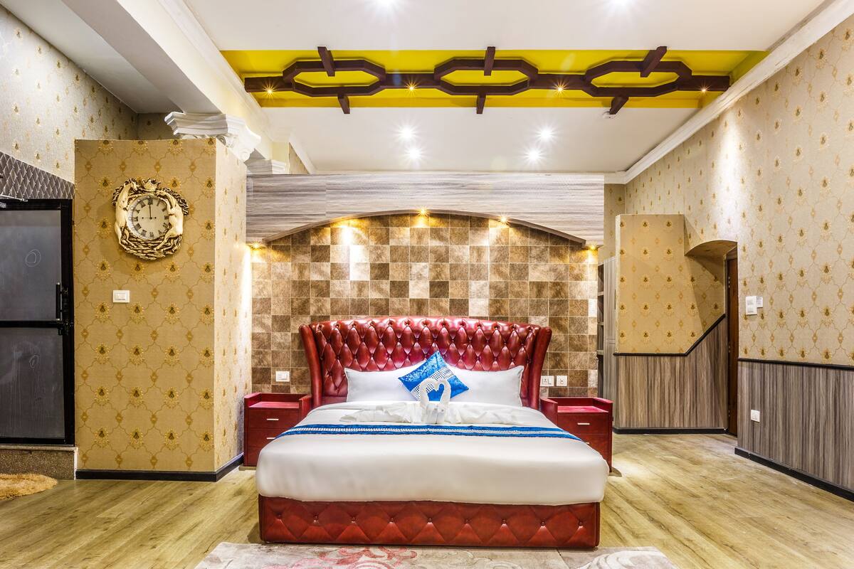 Un dormitorio amplio con una cama grande, un reloj de pared decorativo y un diseño de techo original.