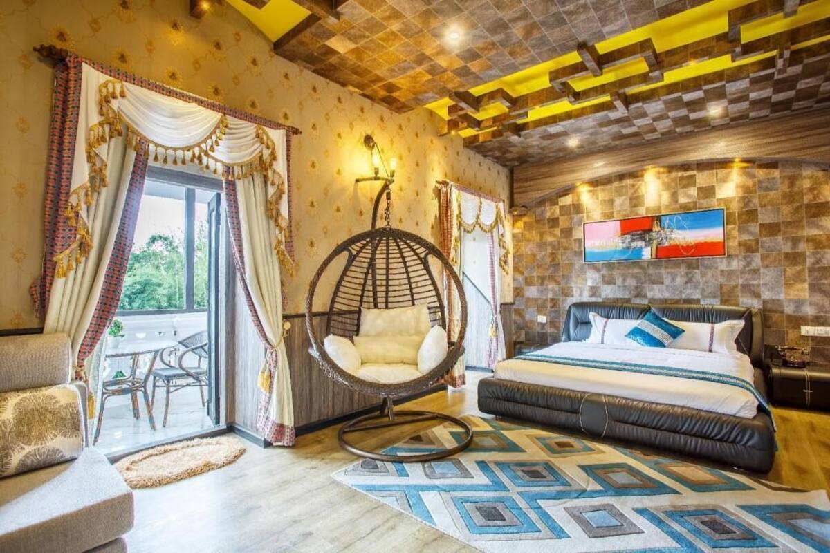 Un dormitorio con cama, una silla colgante, un sofá y vistas al exterior.