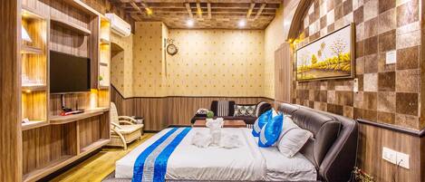 Una habitación de hotel con una cama grande, televisión, escritorio y armario.