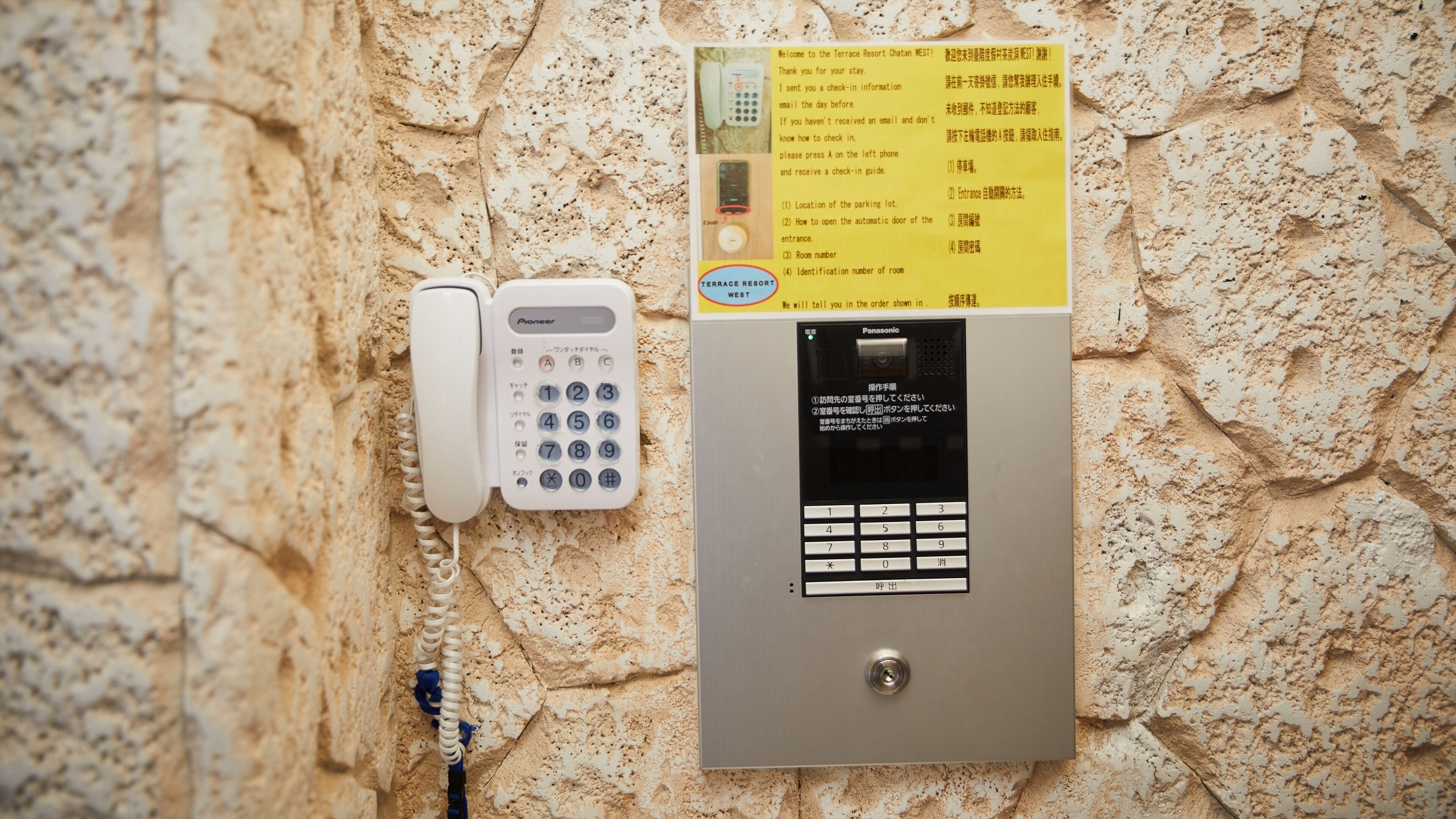 A wall-mounted phone and a digital keypad, likely for room access or information, against a textured stone wall.