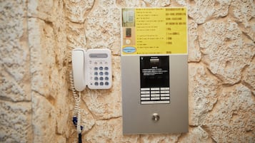 A wall-mounted phone and a digital keypad, likely for room access or information, against a textured stone wall.