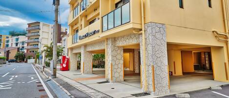 A hotel entrance with a yellow facade, a visible entrance, and a red mailbox.