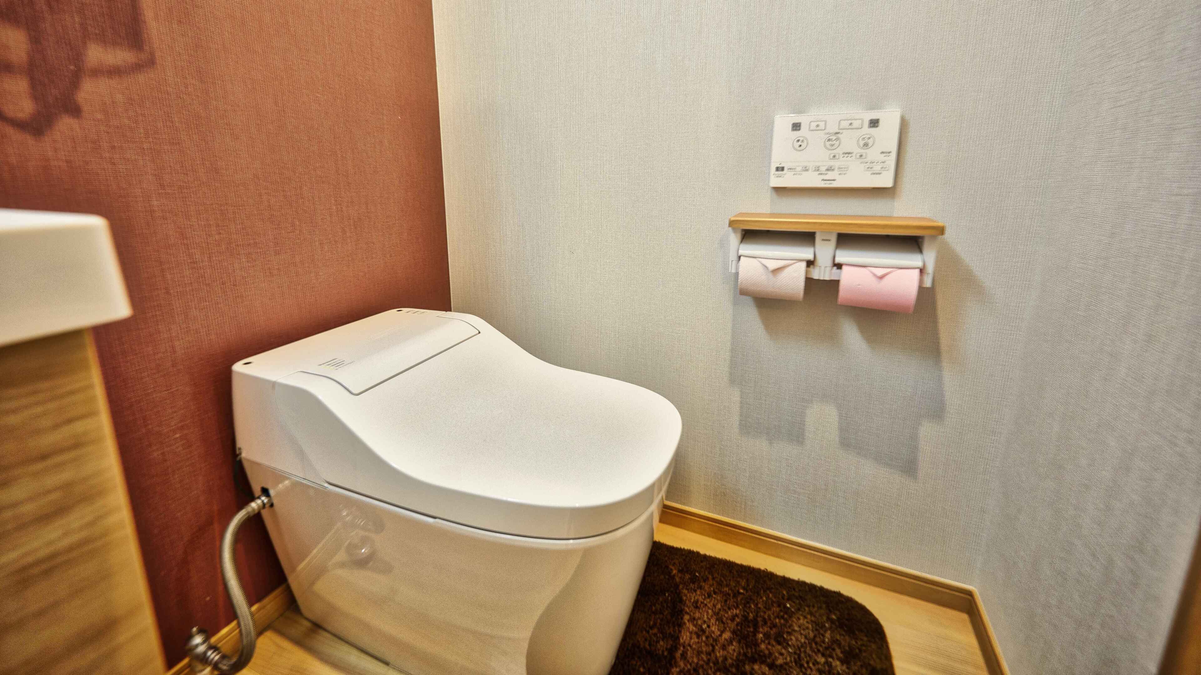 Een moderne badkamer met een wit toilet, een wandmodel papierdispenser en een zichtbare boiler.