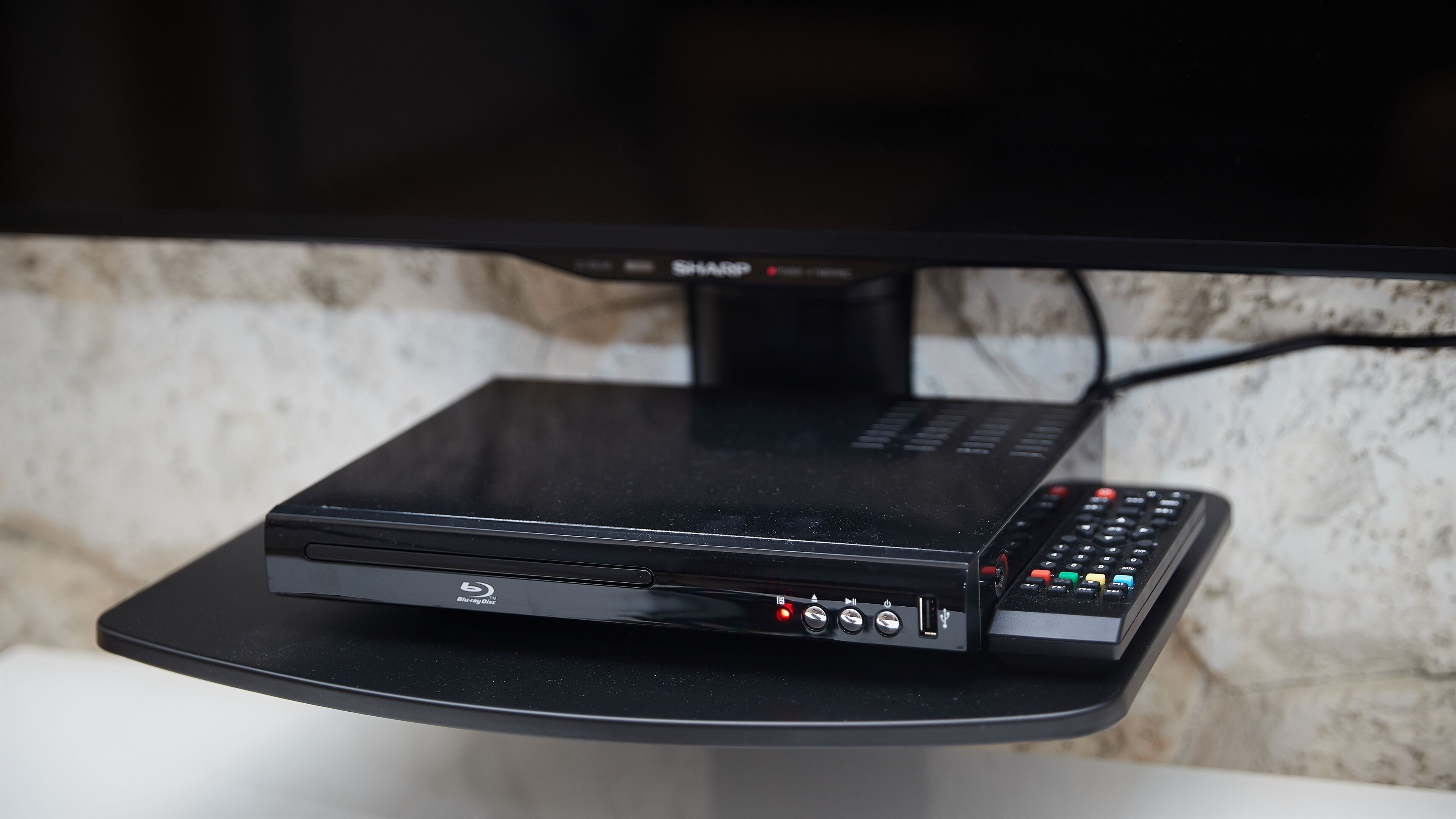 A Blu-ray player on a stand with a remote control.