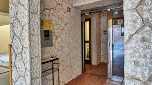 Un ascensor de paredes de piedra con un panel metálico y una pequeña mesa con una bandeja.