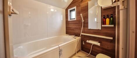 Un baño moderno con una bañera independiente, un inodoro y un espejo con un estante superior.