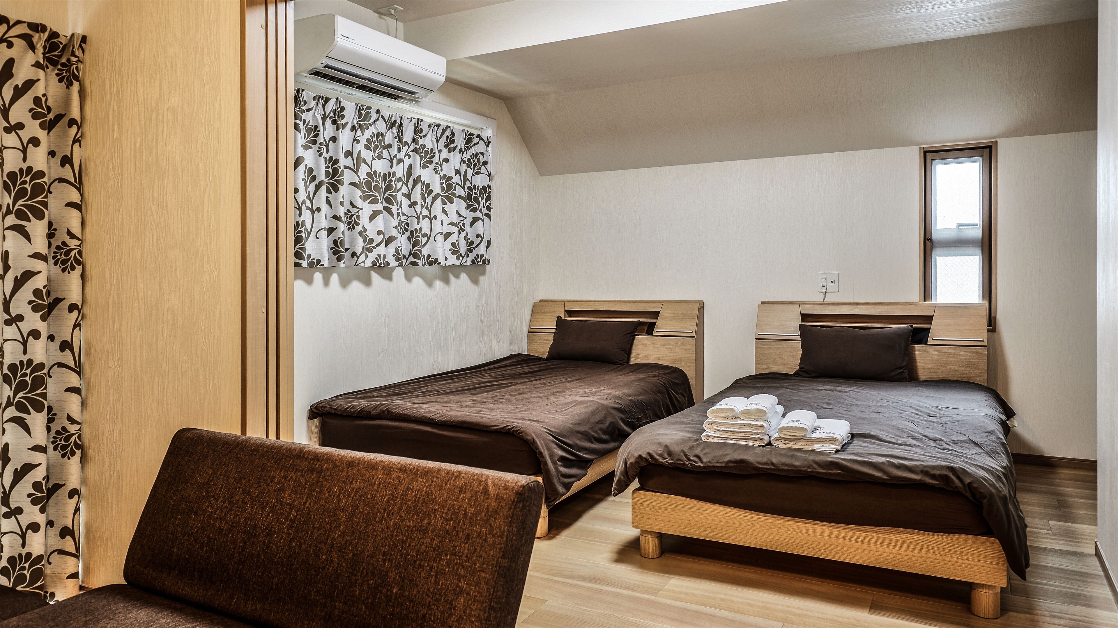 Una habitación con dos camas, una silla y un aire acondicionado.