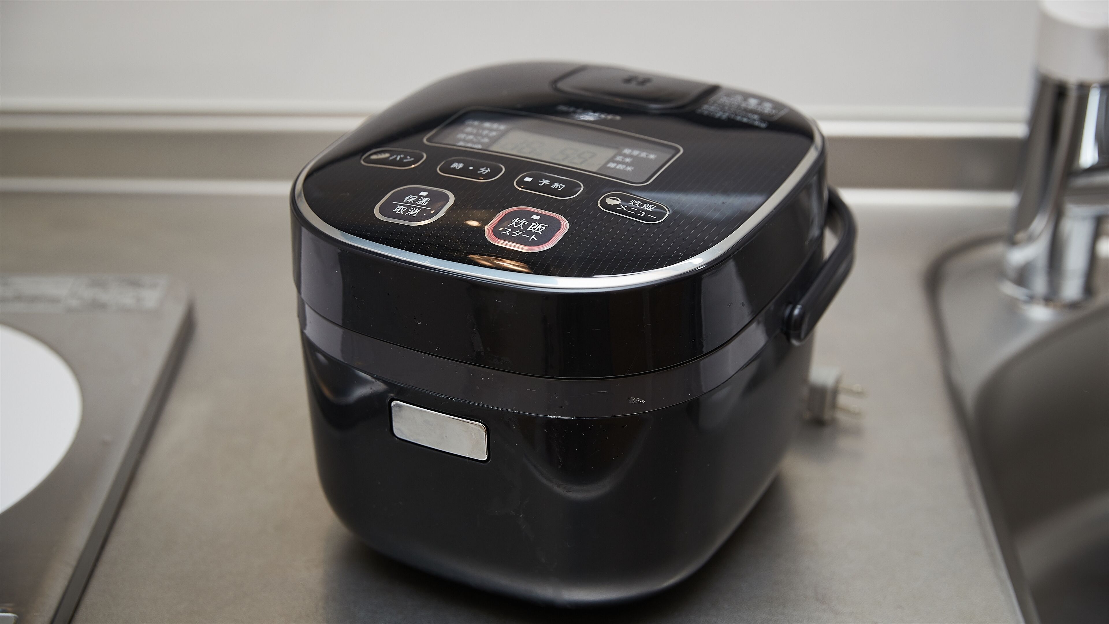 A black electric kettle with a digital display and multiple buttons on a kitchen counter.
