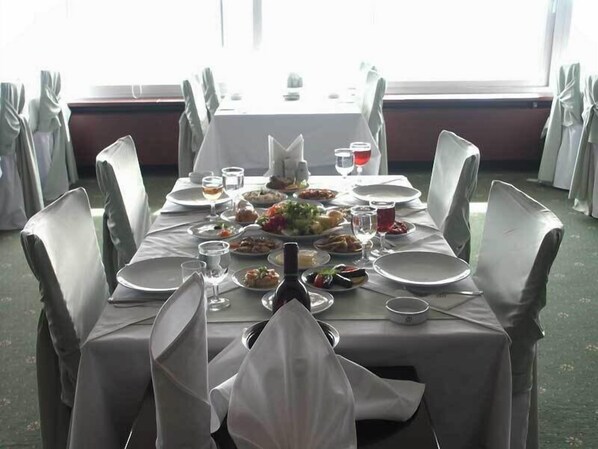 A dining table set for a meal with chairs, plates, glasses, and a bottle.