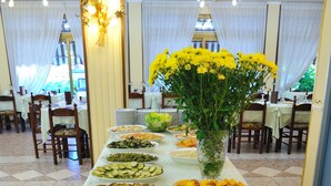 Ein reich gedeckter Buffetstisch mit verschiedenen Speisen und einer Vase mit gelben Blumen.