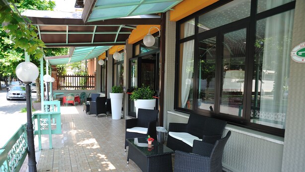 Ein Außenbereich mit Korbmöbeln, Blumentöpfen und einer überdachten Terrasse.