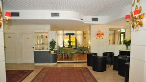 Eine geräumige Lobby mit einer zentralen Sitzecke, einem Empfangsbereich und Blick in den Speisesaal.