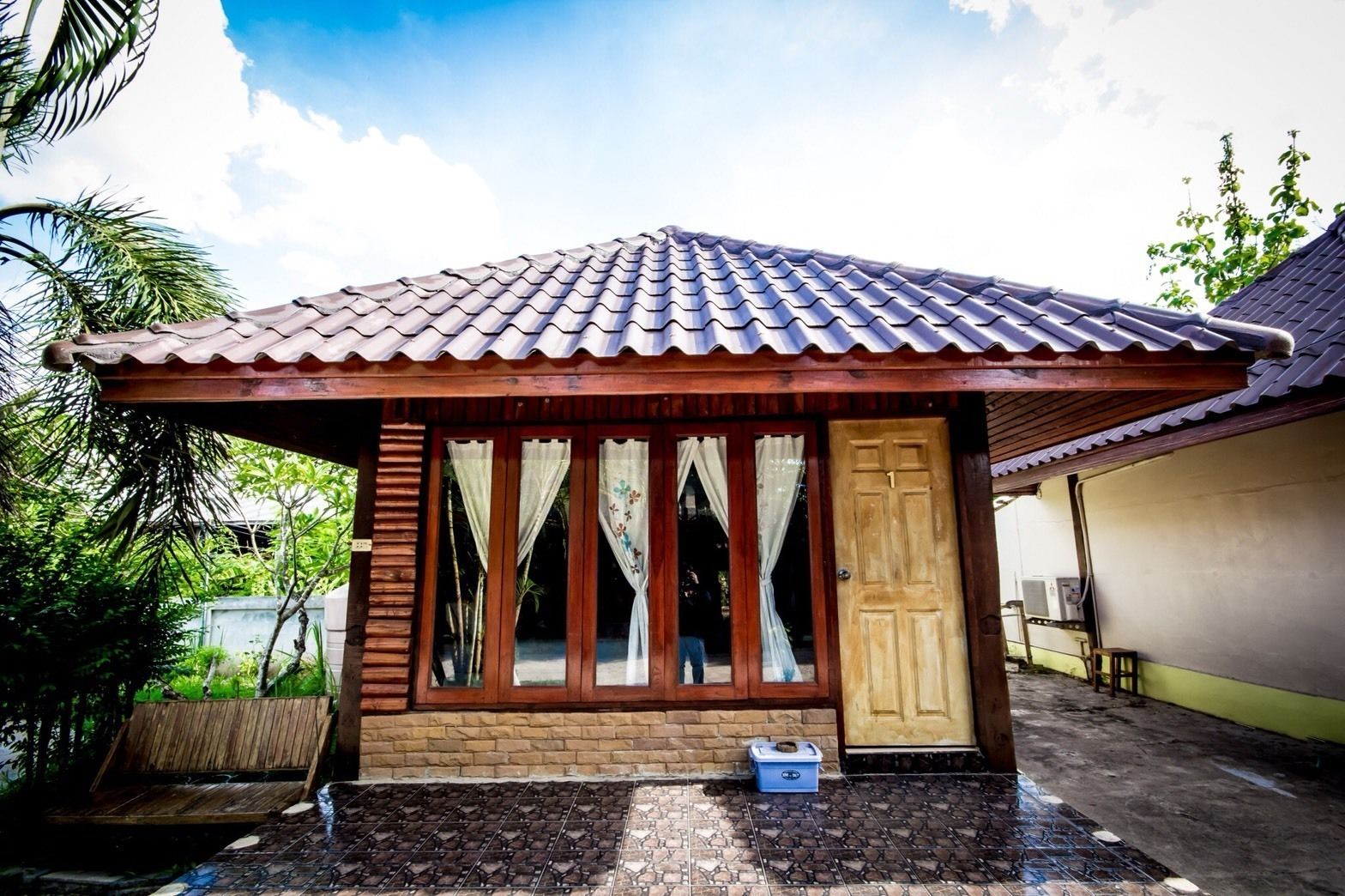A small house with a tiled roof, wooden exterior, and large windows.