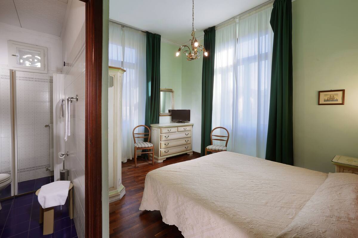 A bedroom with a bed, dresser, chairs, and a mirror.