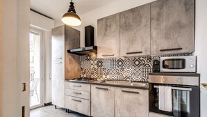 Una cocina moderna con gabinetes grises, un salpicadero con diseño, un microondas empotrado y una estufa a gas.