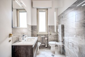 Une salle de bain moderne équipée d’un lavabo, de toilettes et d’une douche.