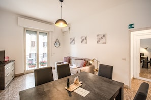 A dining area with a table, chairs, a pendant light, and a view of the outside balcony.