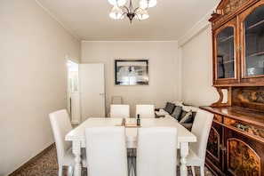 A dining area with a white table and chairs, a wooden cabinet, and a framed picture on the wall.
