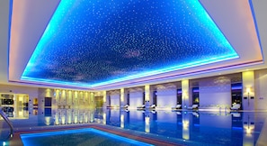 Rebedor d'hotel modern amb una piscina reflectant, un disseny de sostre estrellat i una zona de seients amb taules i cadires.