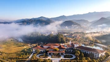 A large estate with multiple buildings, a central courtyard, and a surrounding landscape with mountains and fog.